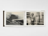 Now Is Always by Vaune Trachtman, hardcover art book shown open to photogravures called Co-op City and Singlet. Co-op City shows a building with light streaks; Singlet shows a youth in a bathing suit surrounded by skyscrapers.