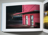 Open book showing a photograph of a pink building at night.