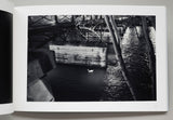 Open book displaying a black and white photograph of a canal with a bridge and a duck.