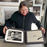 Visual artist Vaune Trachtman in her studio, holding the Collector’s Edition of Now Is Always, which shows the presentation box with signed photogravure and the cloth-covered book.